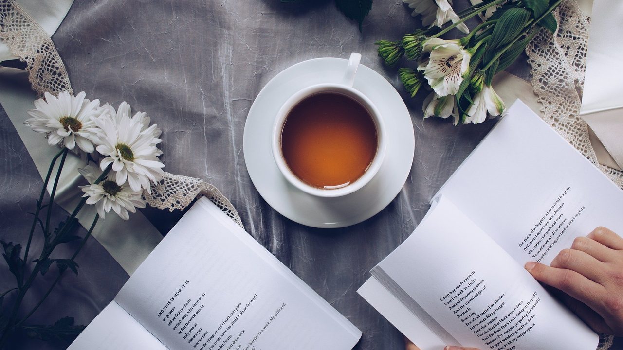 Dos personas leyendo un texto en inglés con una taza de té sobre la mesa